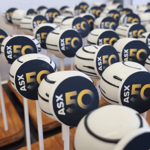 Edible branded cakepops arranged on sticks with a blurred indoor background.