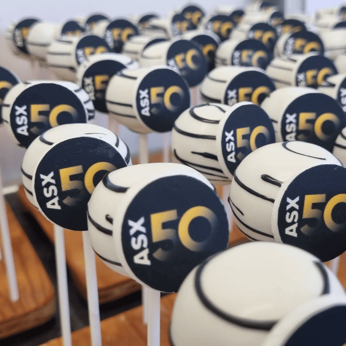 Edible branded cakepops arranged on sticks with a blurred indoor background.