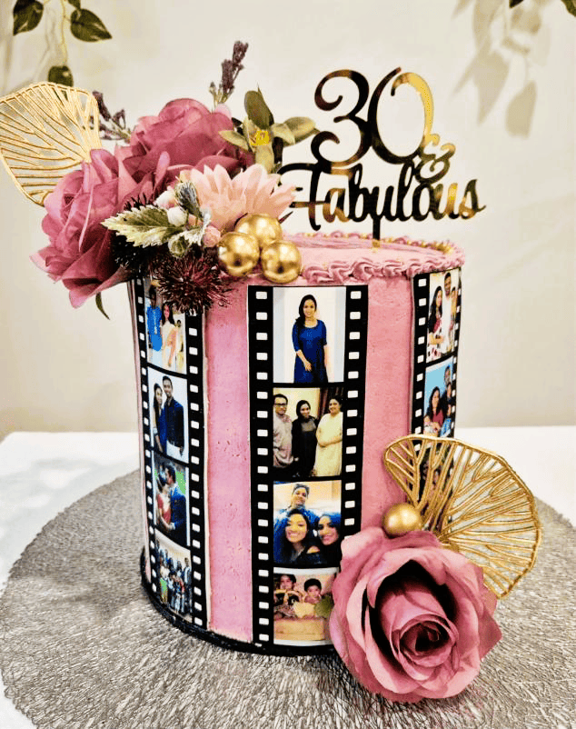 Decorative cake with pink flowers, gold accents, edible printed icing film strips with personal photos and '30 & Fabulous' topper on a neutral background